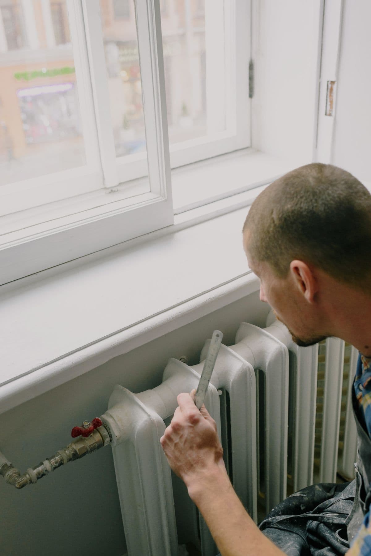 Engineer checking a radiator beneath a bright window