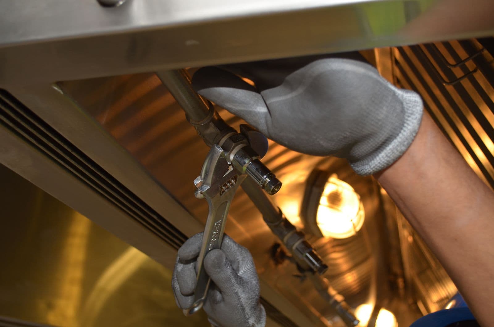 Engineer working with a spanner under a sink
